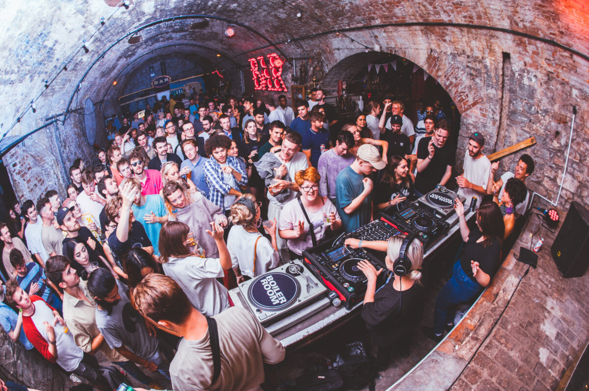 A crowd of people in Loco Klub dancing and listening to a DJ.