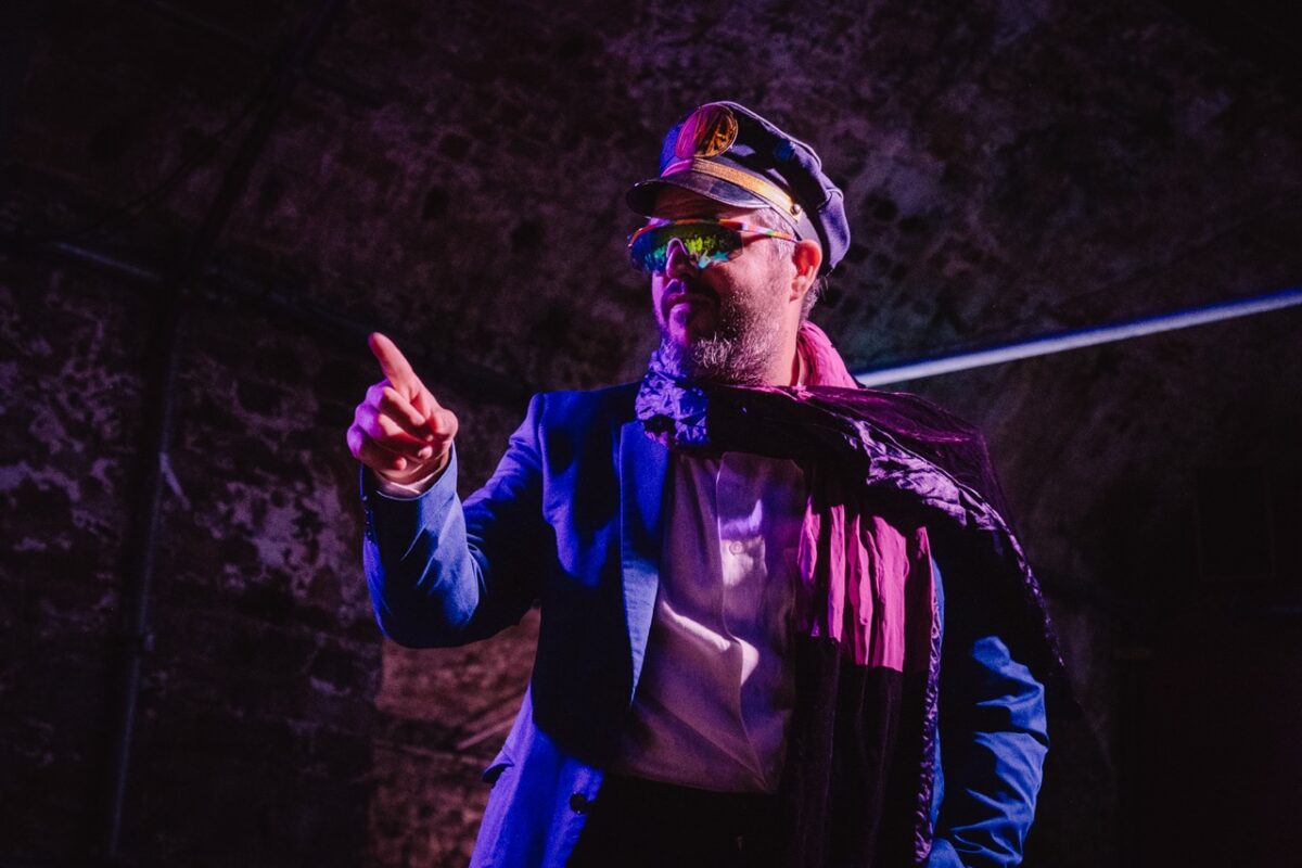 A performer in a train conductors uniform pointing into the distance. 
