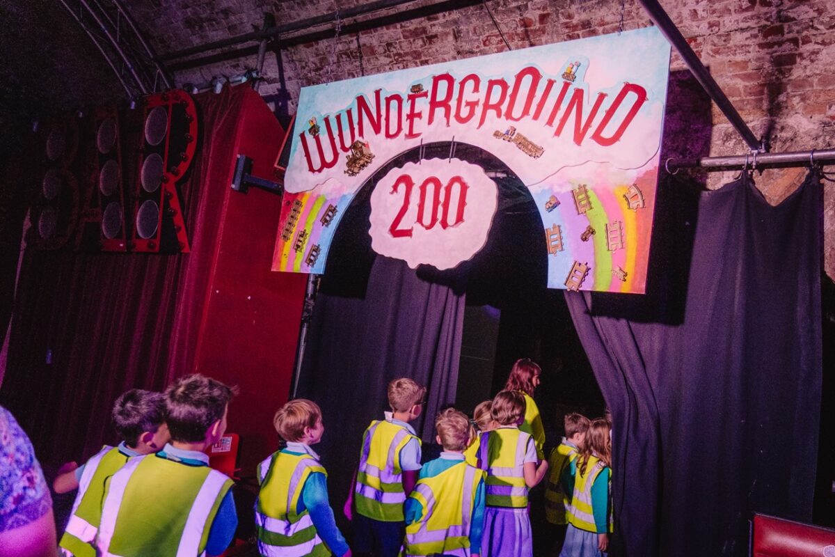 Children going through a curtain underneath a Wunderground 200 sign. 