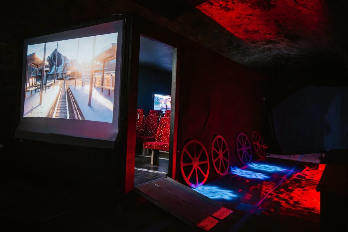 A room with seats in it with a projection of a train track on the outside. 