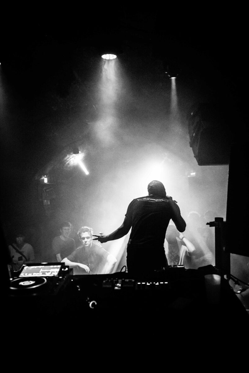 A performer stood on stage singing into the mic. the image is greyscale.